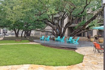 A patio with blue chairs and grass and trees